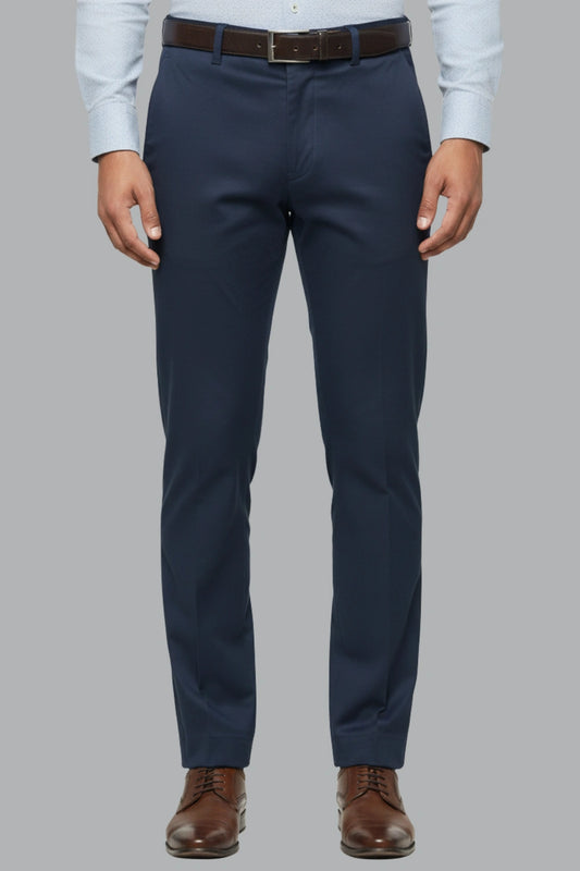 Dark blue cotton pants worn with a light blue shirt and brown shoes on a gray background
