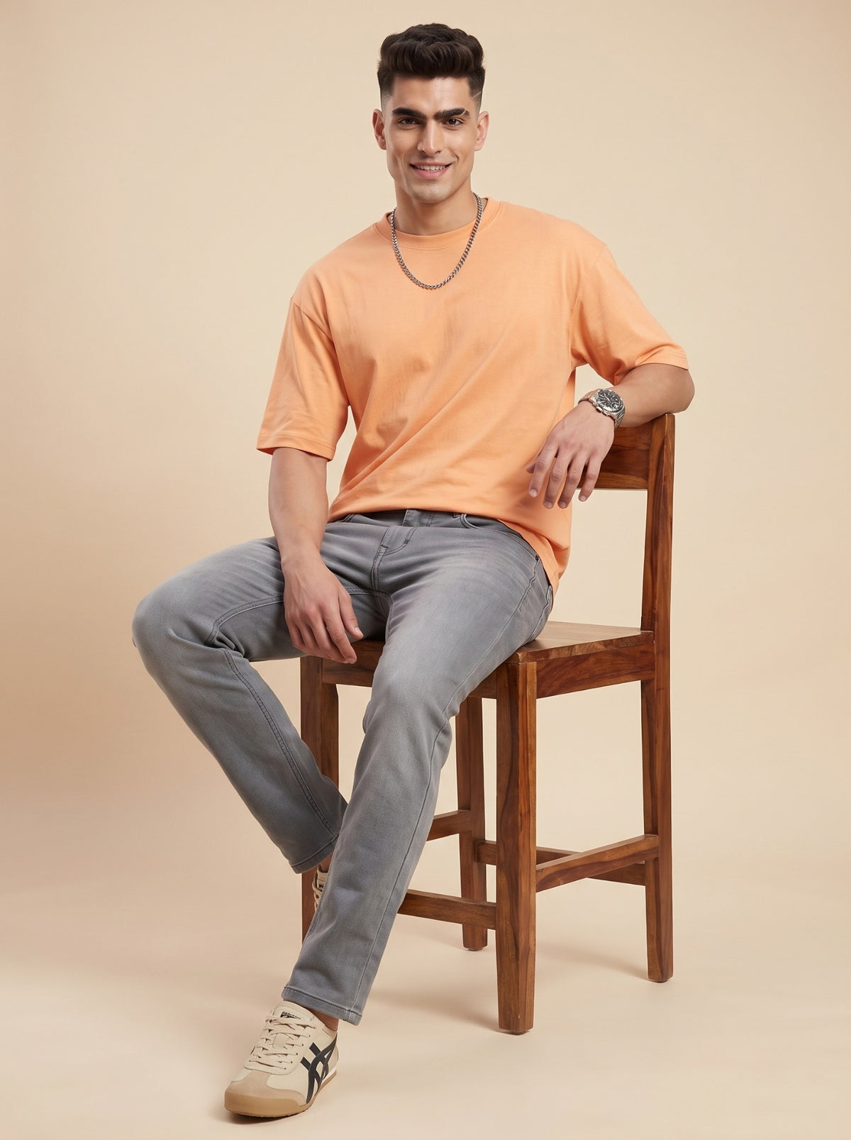 Man wearing ash grey straight fit jeans seated on a stool