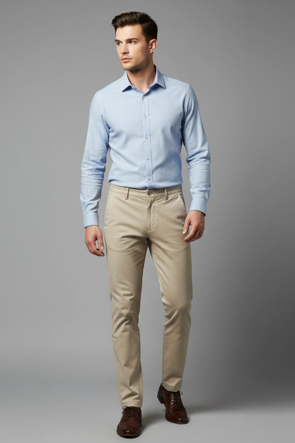 Man wearing a light blue shirt and beige  cotton pants on a gray background