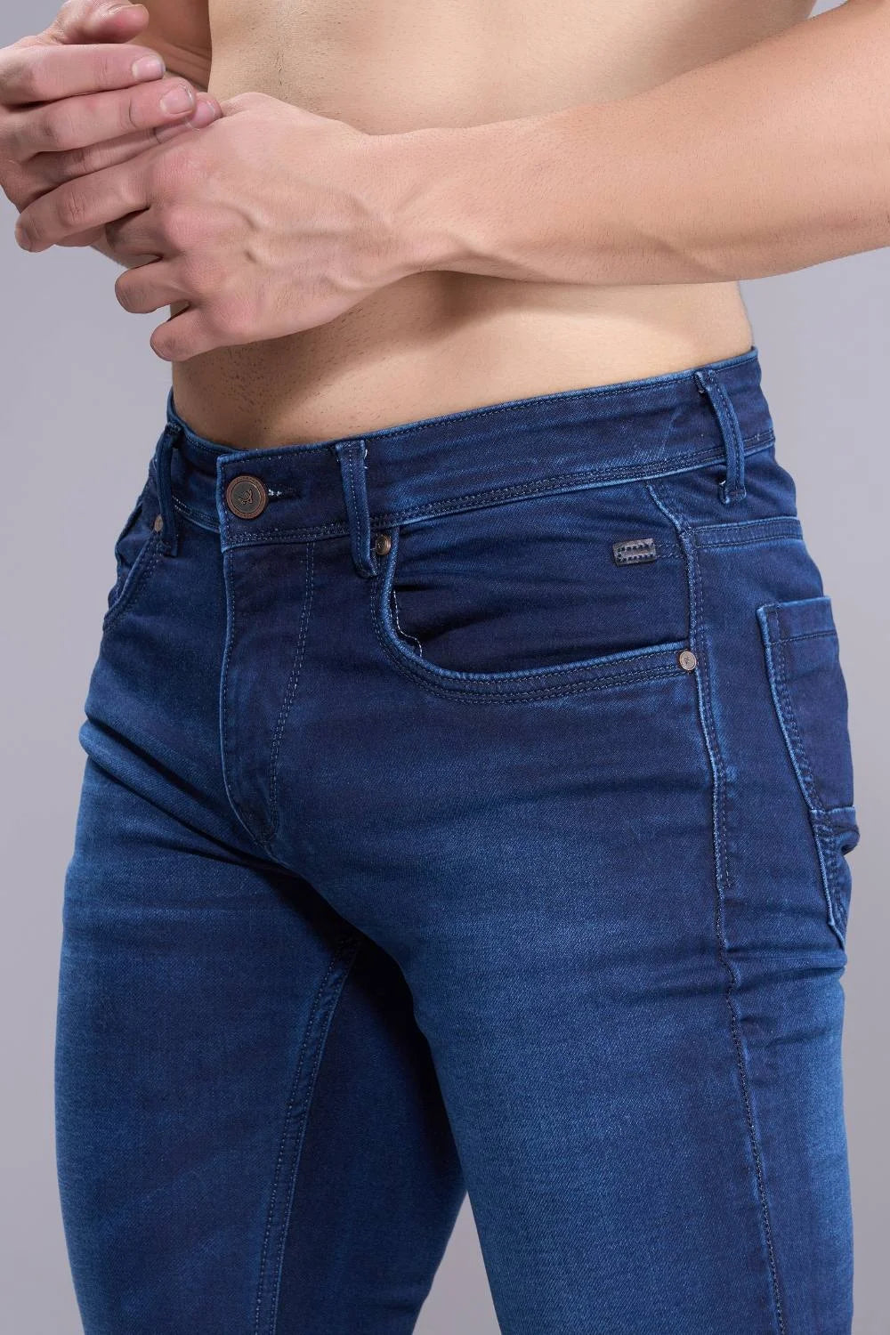 Close-up of blue denim fabric showing texture and stitching of regular fit jeans.
