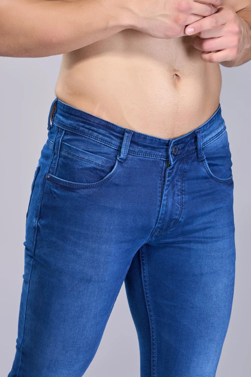 Waist and pocket close-up of men’s blue regular fit jeans.
