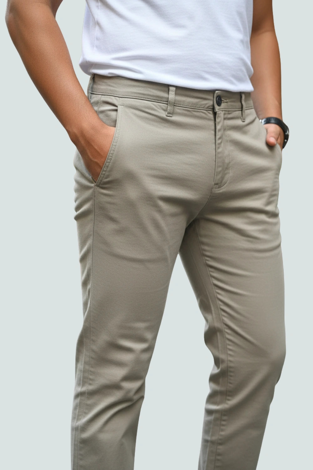 Person wearing brown cotton pants and a white shirt on a light gray background