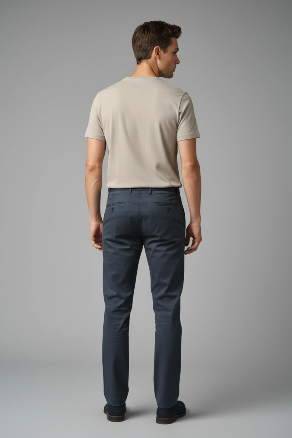 Man wearing a beige t-shirt and dark blue cotton pants on a gray background