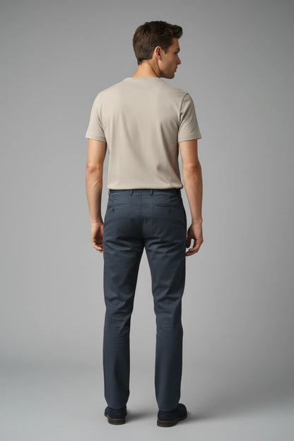 Man wearing a beige t-shirt and dark blue cotton pants on a gray background