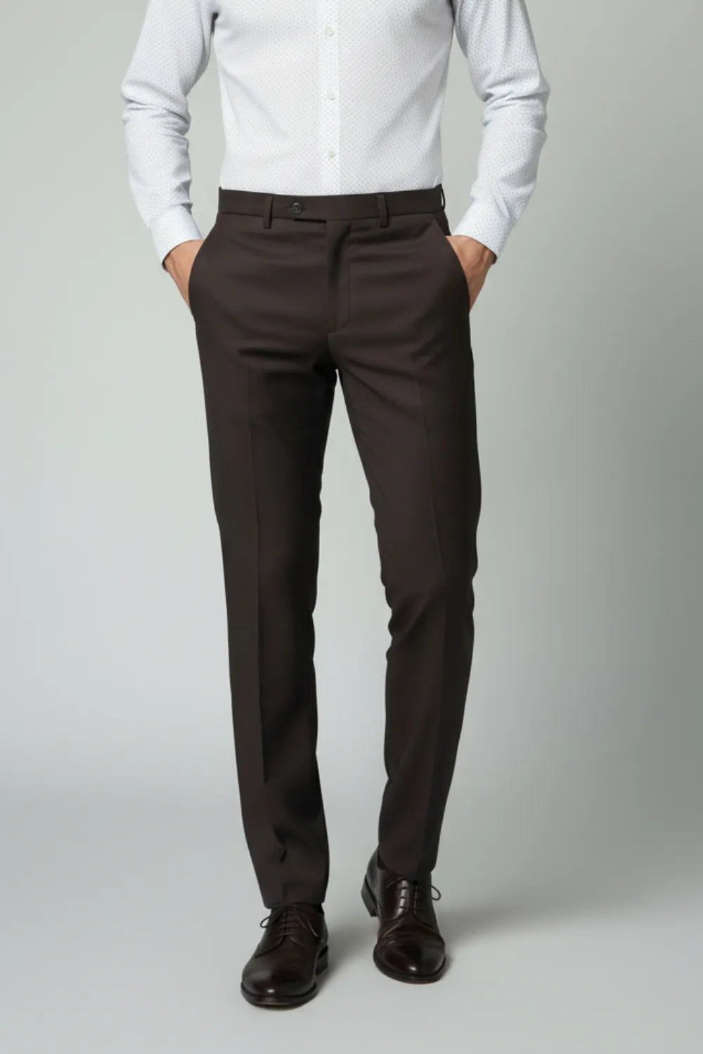 Person wearing a white shirt and dark brown pants on a plain background