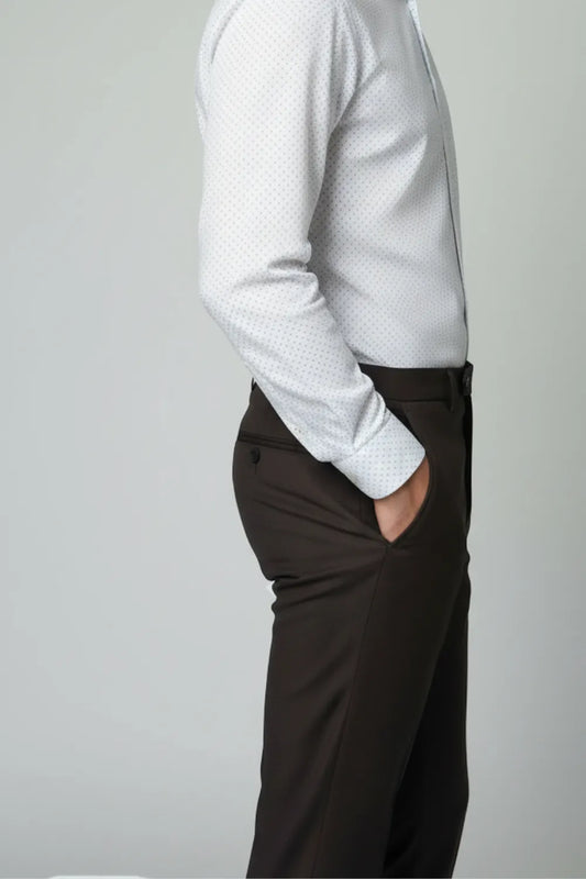 Person wearing a white shirt and dark brown pants on a plain background showing side view