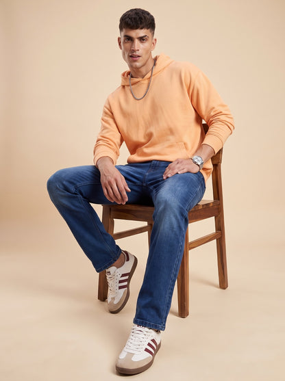 Man wearing deep indigo straight fit jeans seated on a stool