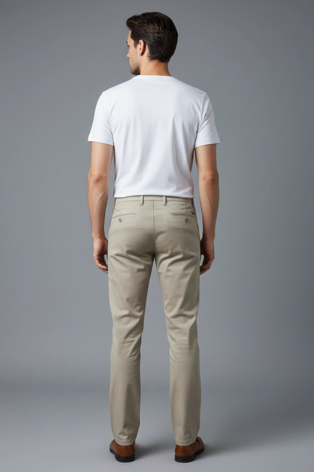 A back side-angle shot of a model showing the tapered fit of the beige cotton pant