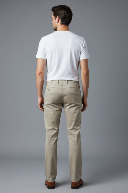 A back side-angle shot of a model showing the tapered fit of the beige cotton pant