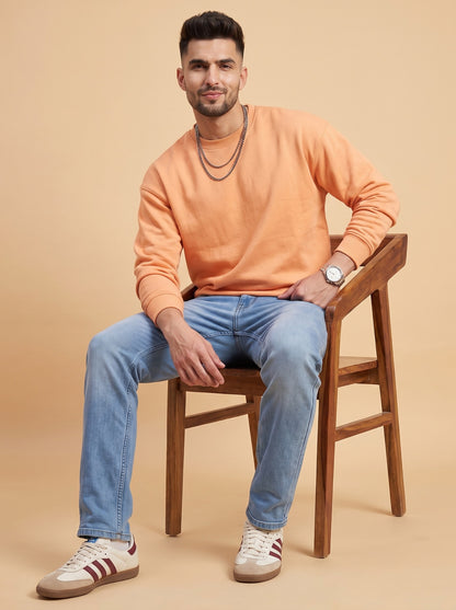 Man wearing light blue straight fit jeans seated on a stool