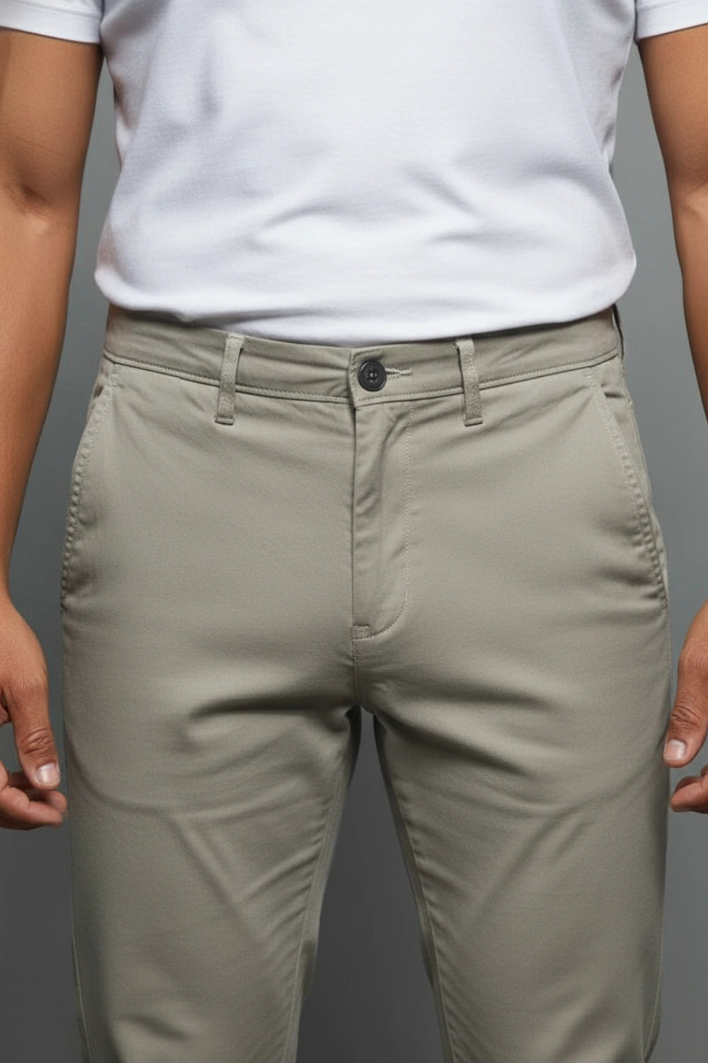 Person wearing beige pants and a white shirt on a gray background