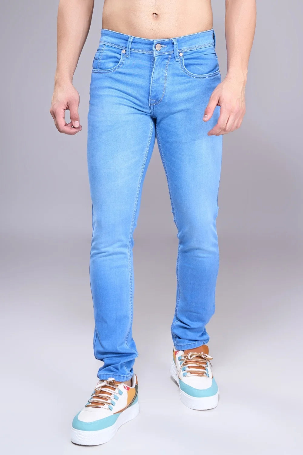 Man showcasing lightweight regular-fit light blue denim jeans in a studio pose
