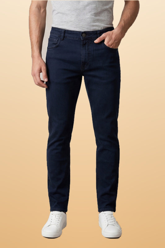 Men's dark blue slim fit jeans on orange-beige studio background