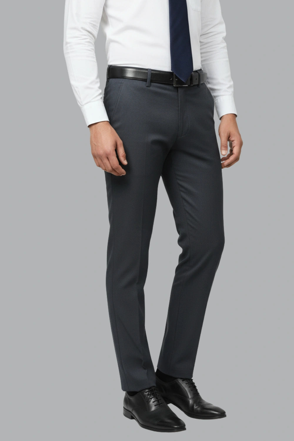 Person wearing a white shirt, dark tie, black belt, and dark blue cotton pants on a gray background