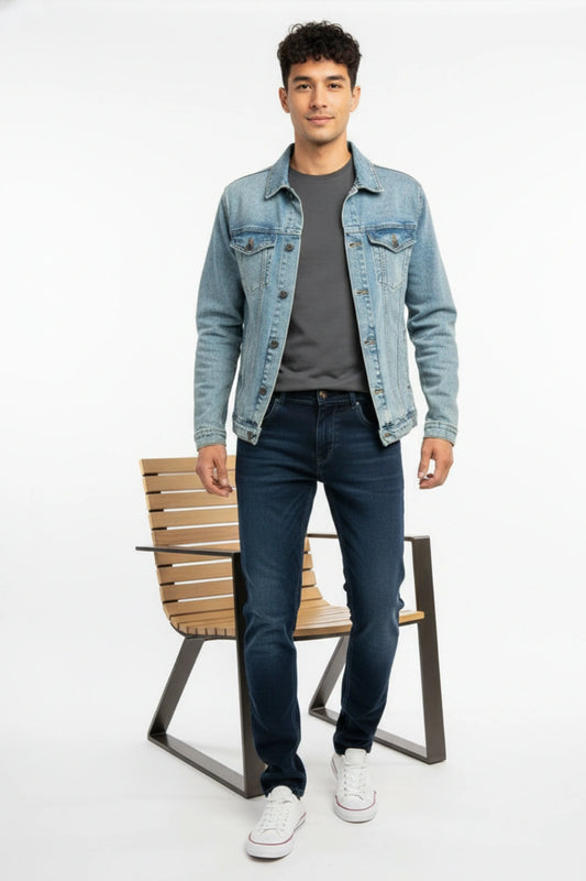 A man wearing dark blue slim fit jeans paired with a casual blazer in a modern urban setting.