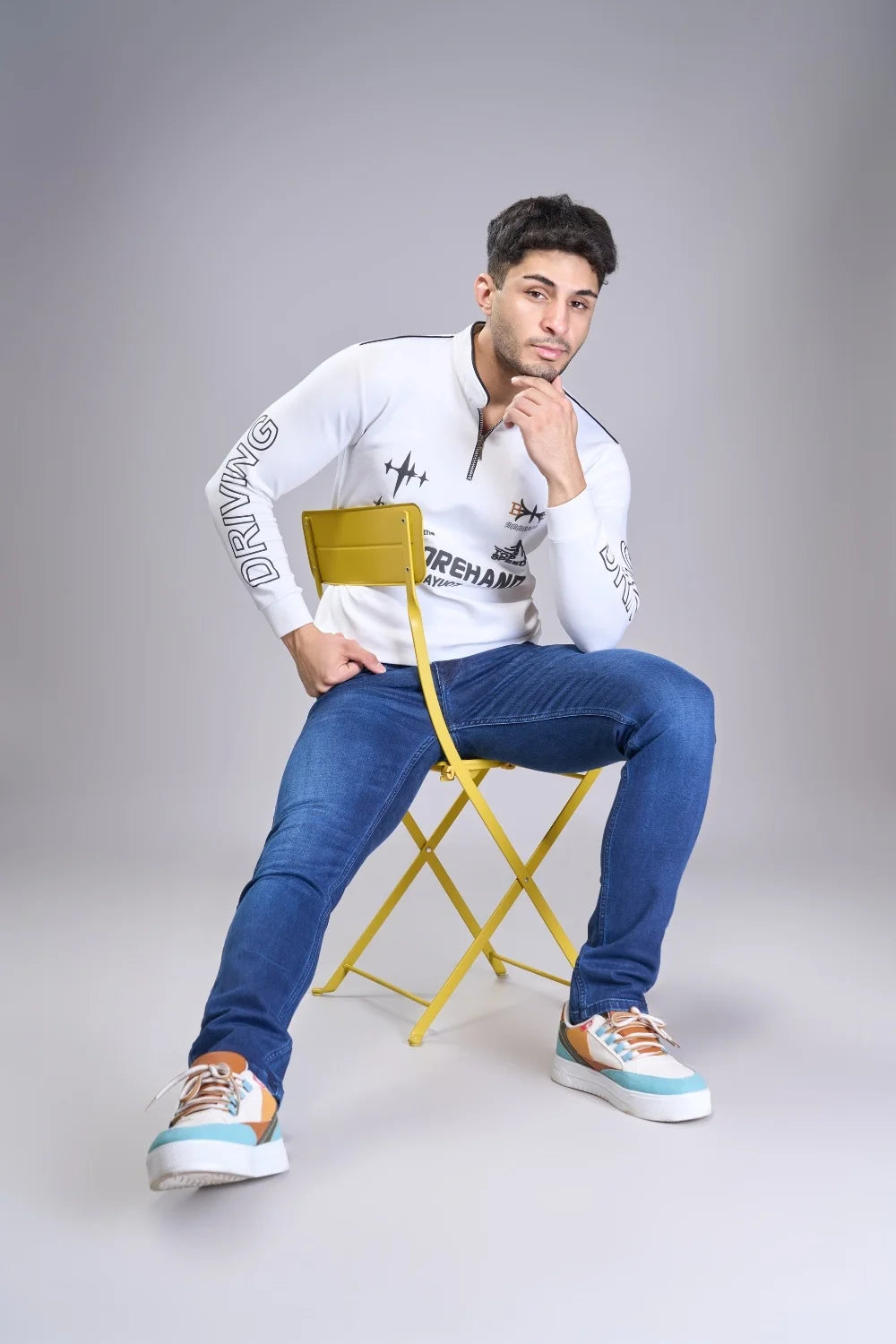 Sitting pose wearing men’s blue regular fit jeans with classic styling
