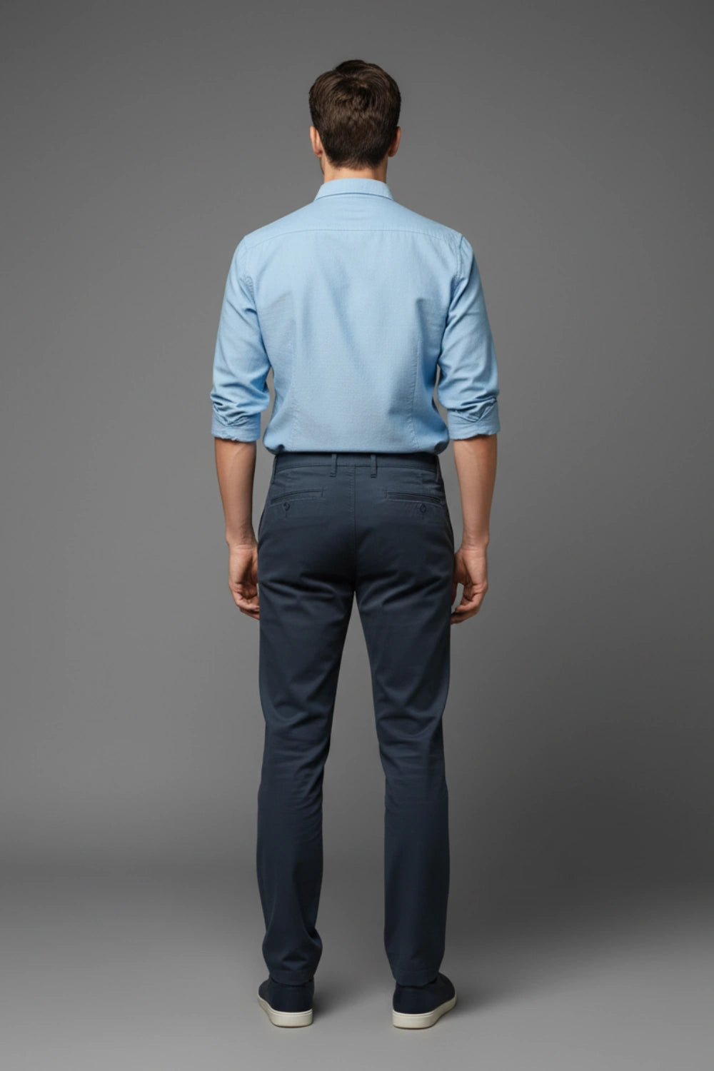 Man wearing a light blue shirt and dark blue pants on a gray background