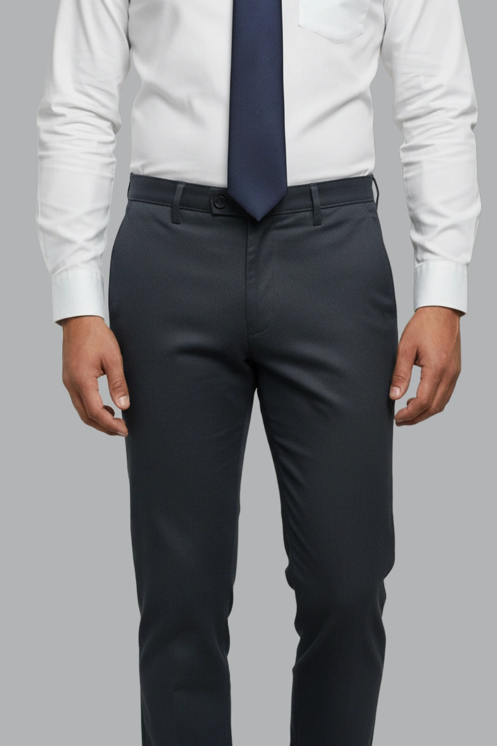 Person wearing a white shirt, navy tie, and blue pants on a gray background