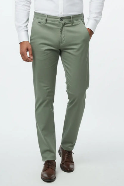 Person wearing olive green cotton pants with a white shirt and brown shoes on a white background