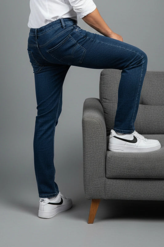 Side view profile of men's slim fit jeans paired with a black denim jacket and white sneakers to show the tailored silhouette.