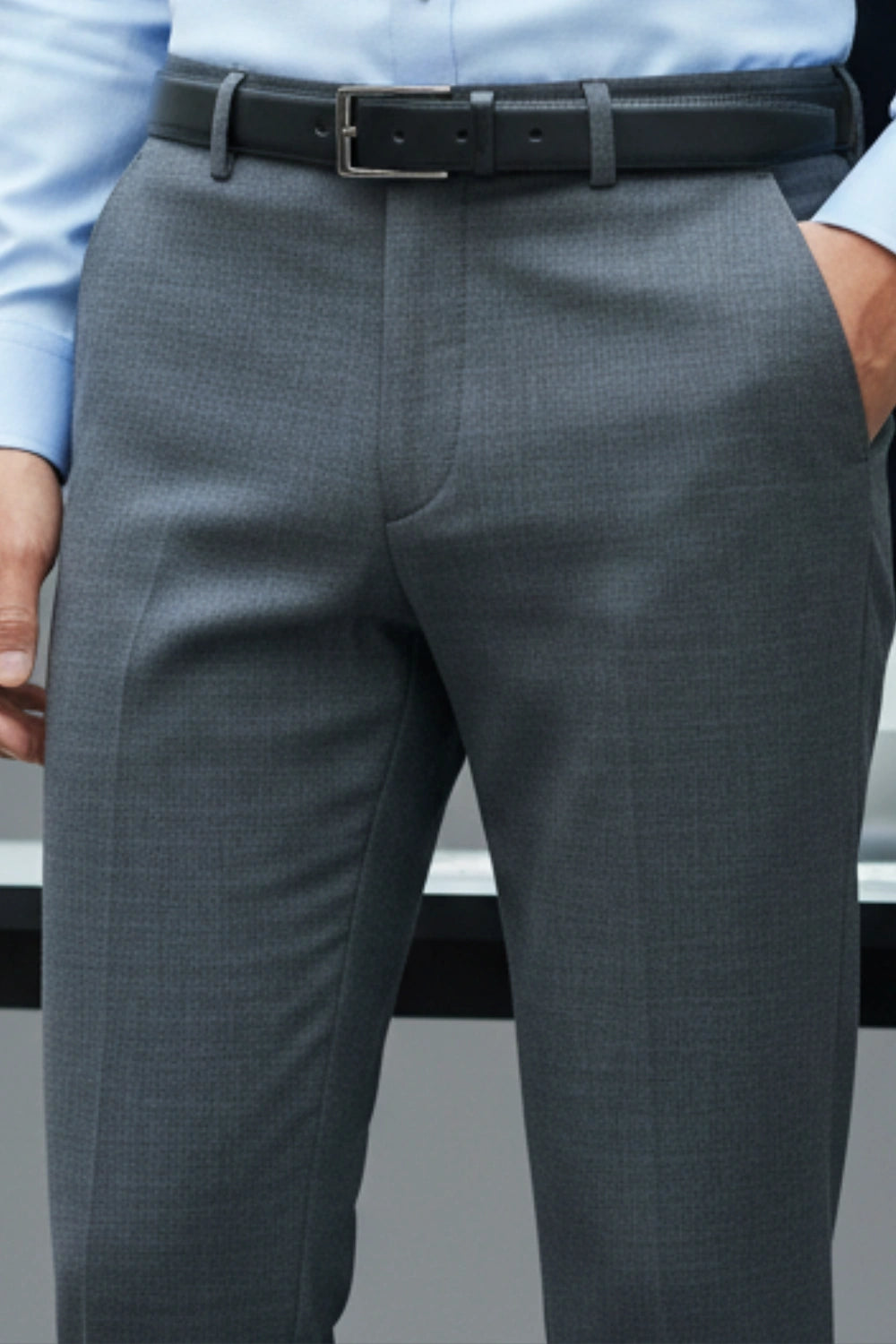 Gray suit pants with a black belt and light blue shirt on a gray background