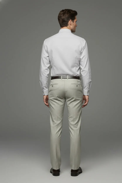 Man wearing a light gray shirt and formal pants against a gray background